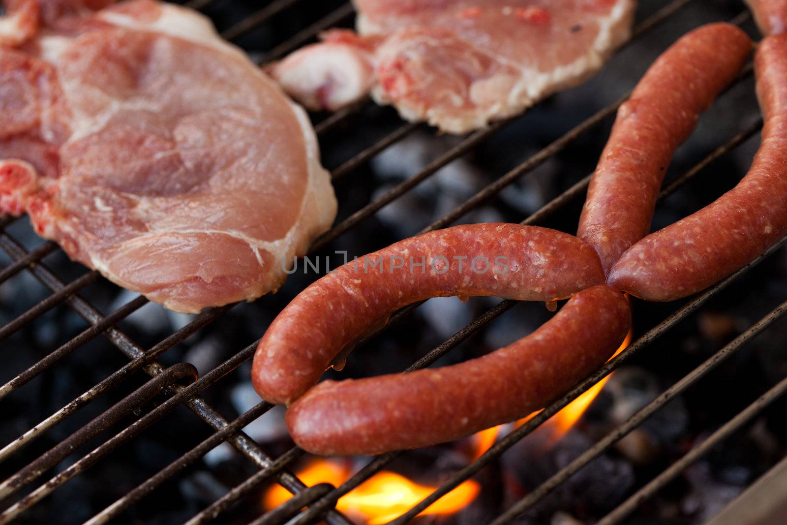 Several type of meats being cooked on a barbecue