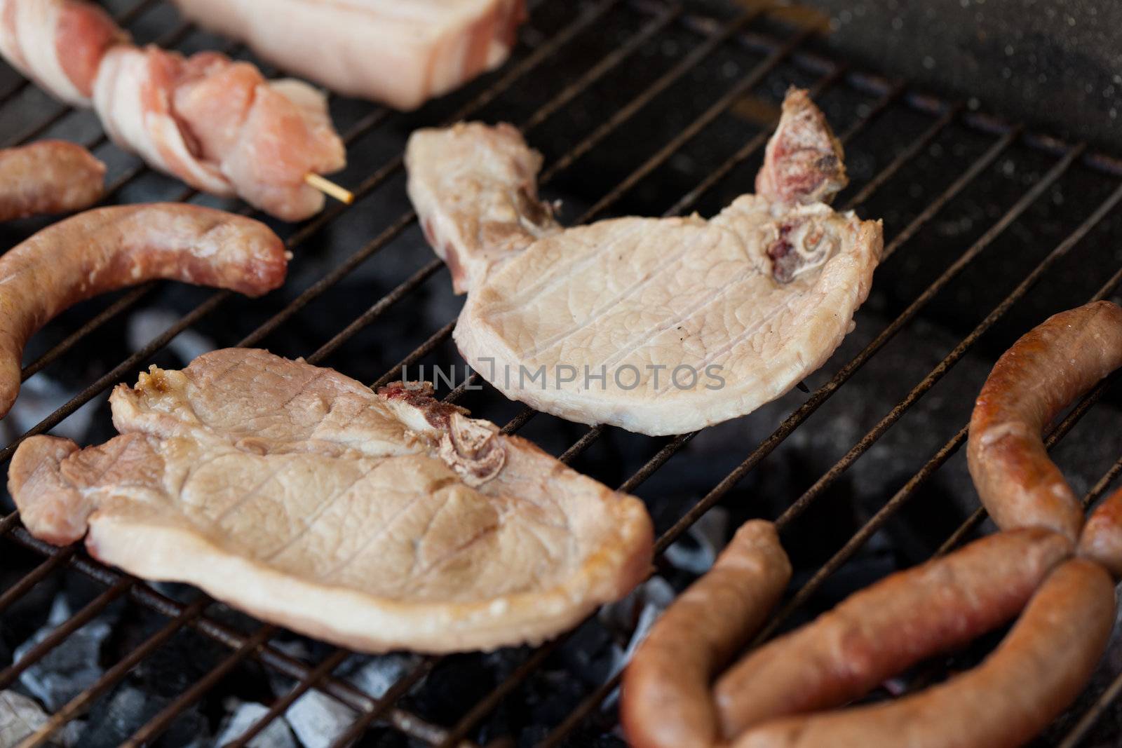 Several type of meats being cooked on a barbecue