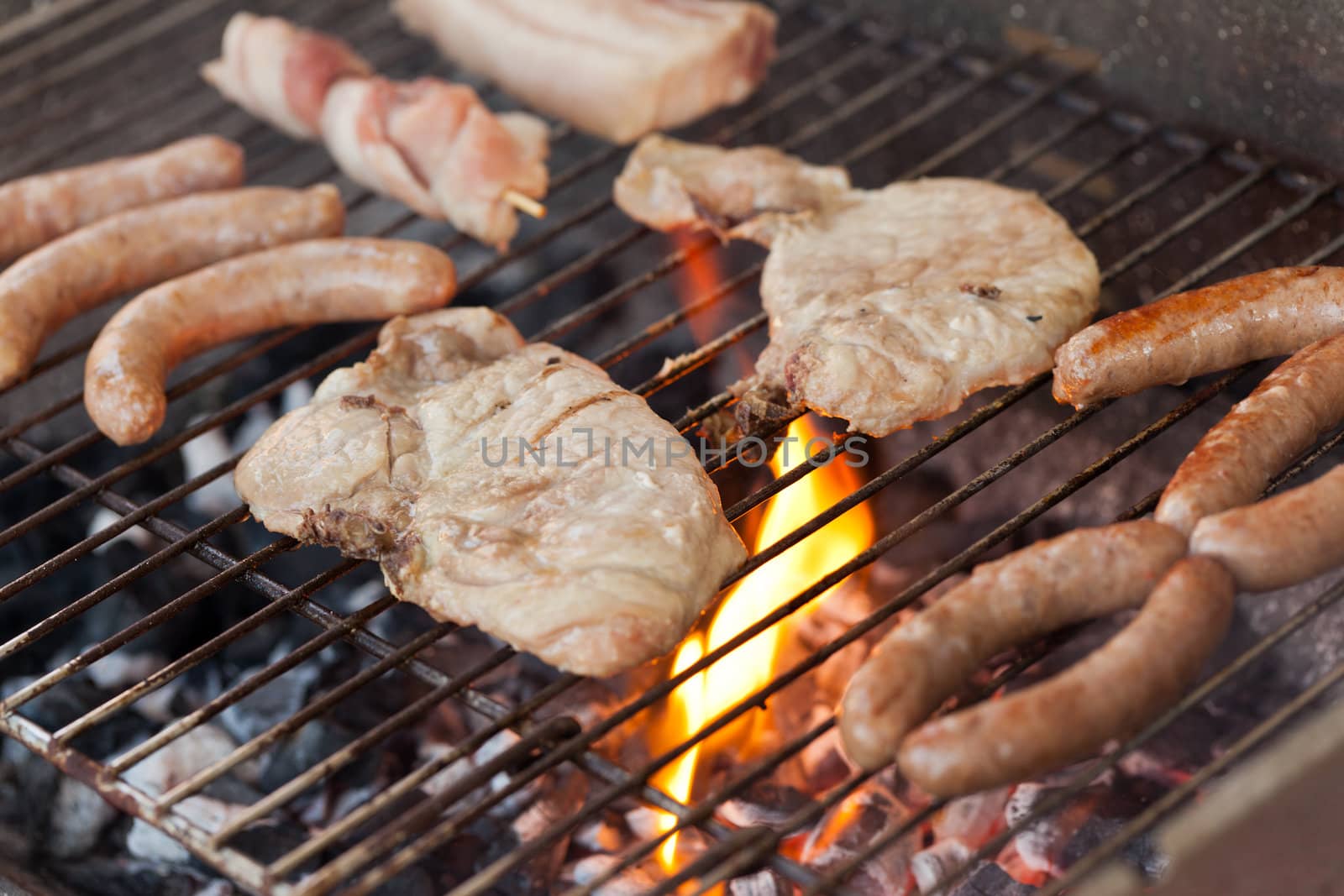 Several type of meats being cooked on a barbecue