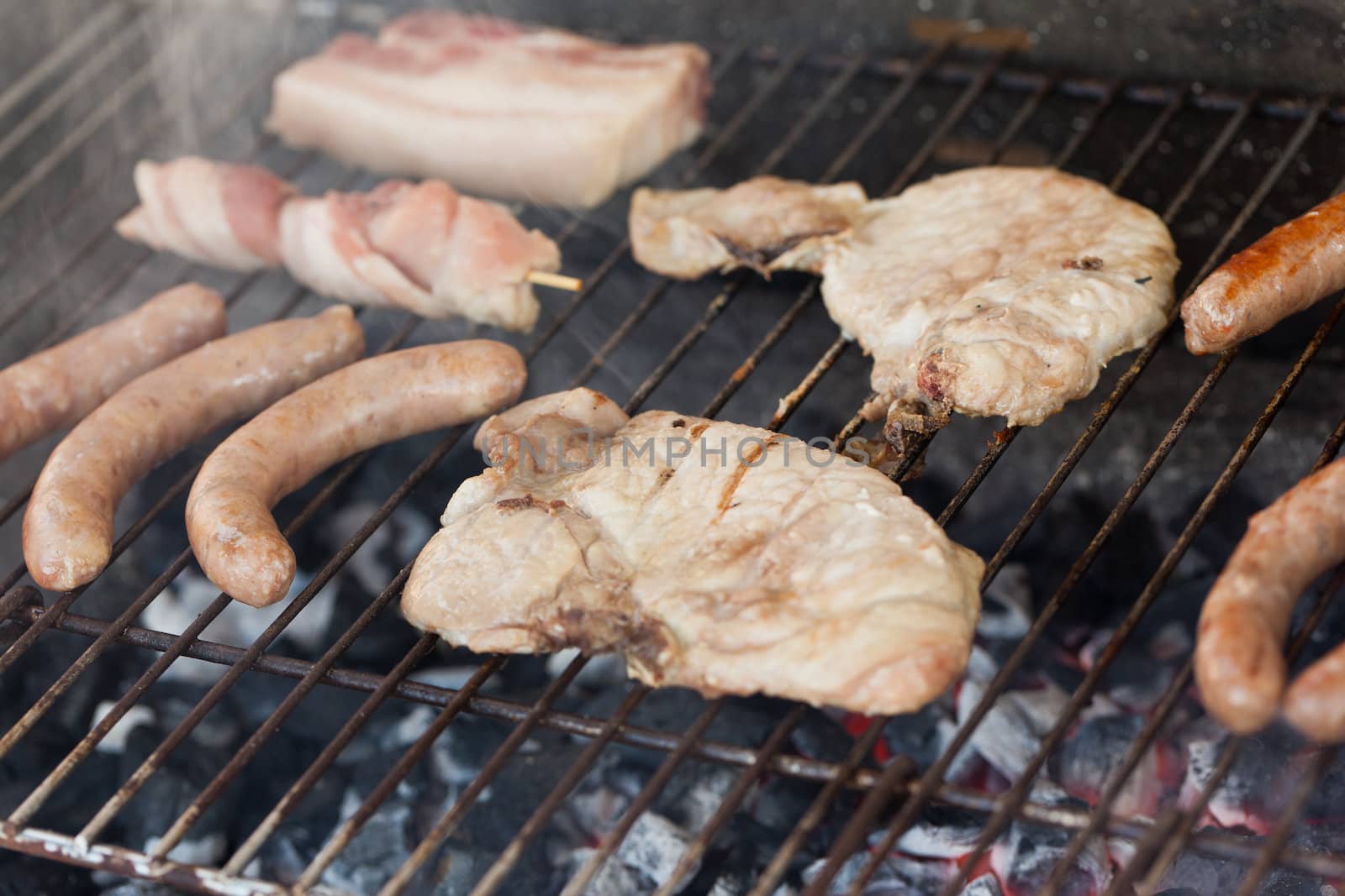 Several type of meats being cooked on a barbecue