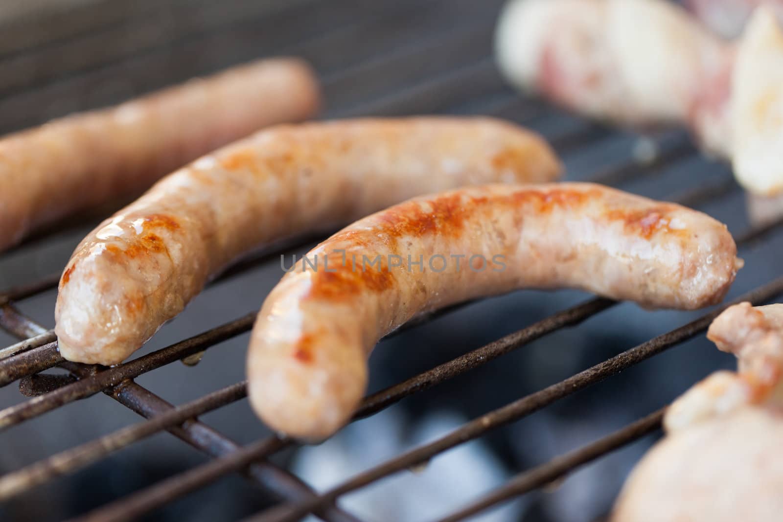 Several type of meats being cooked on a barbecue