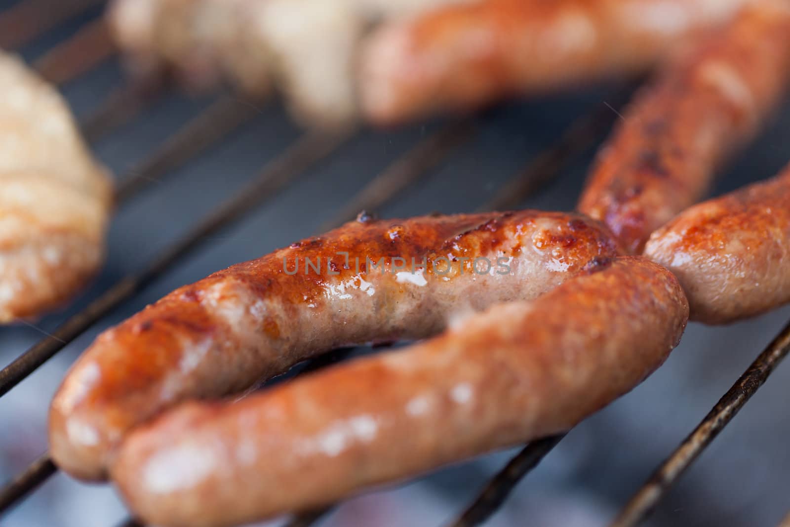 Several type of meats being cooked on a barbecue