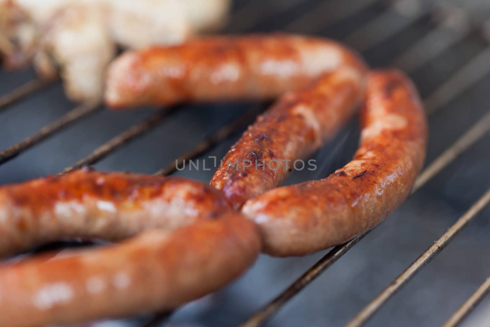 Several type of meats being cooked on a barbecue