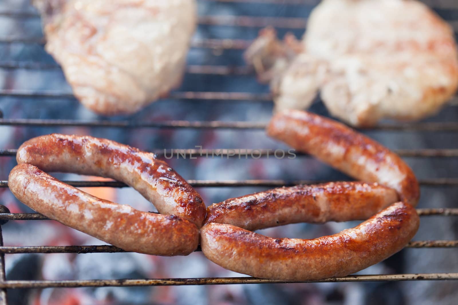 Several type of meats being cooked on a barbecue