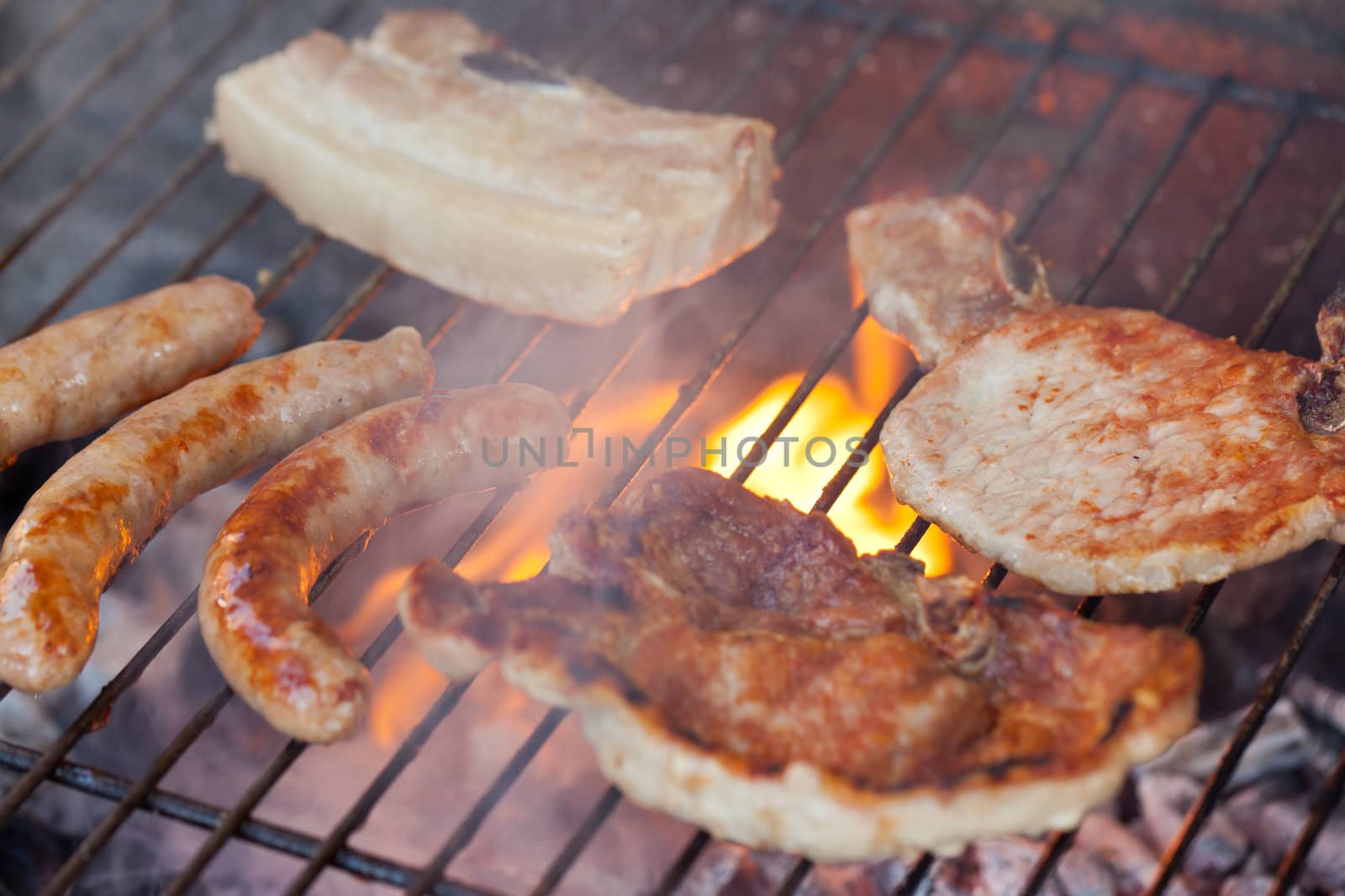 Several type of meats being cooked on a barbecue