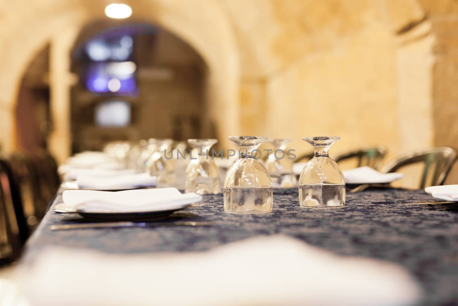 Long restaurant table with dishes, glasses, forks and knives