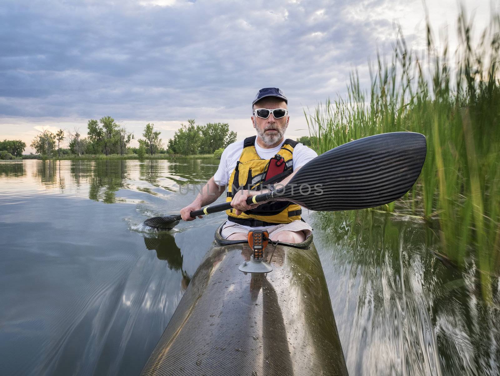 senior paddler in a racing sea kayak  on a calm lake, Fort Collins, Colorado