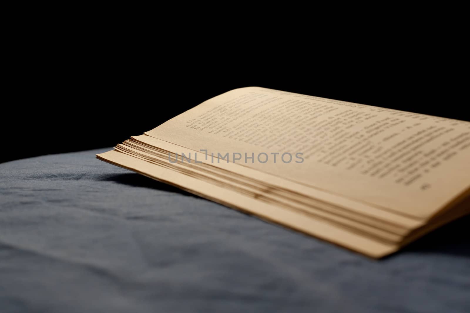An old book on a bed with dark sheet