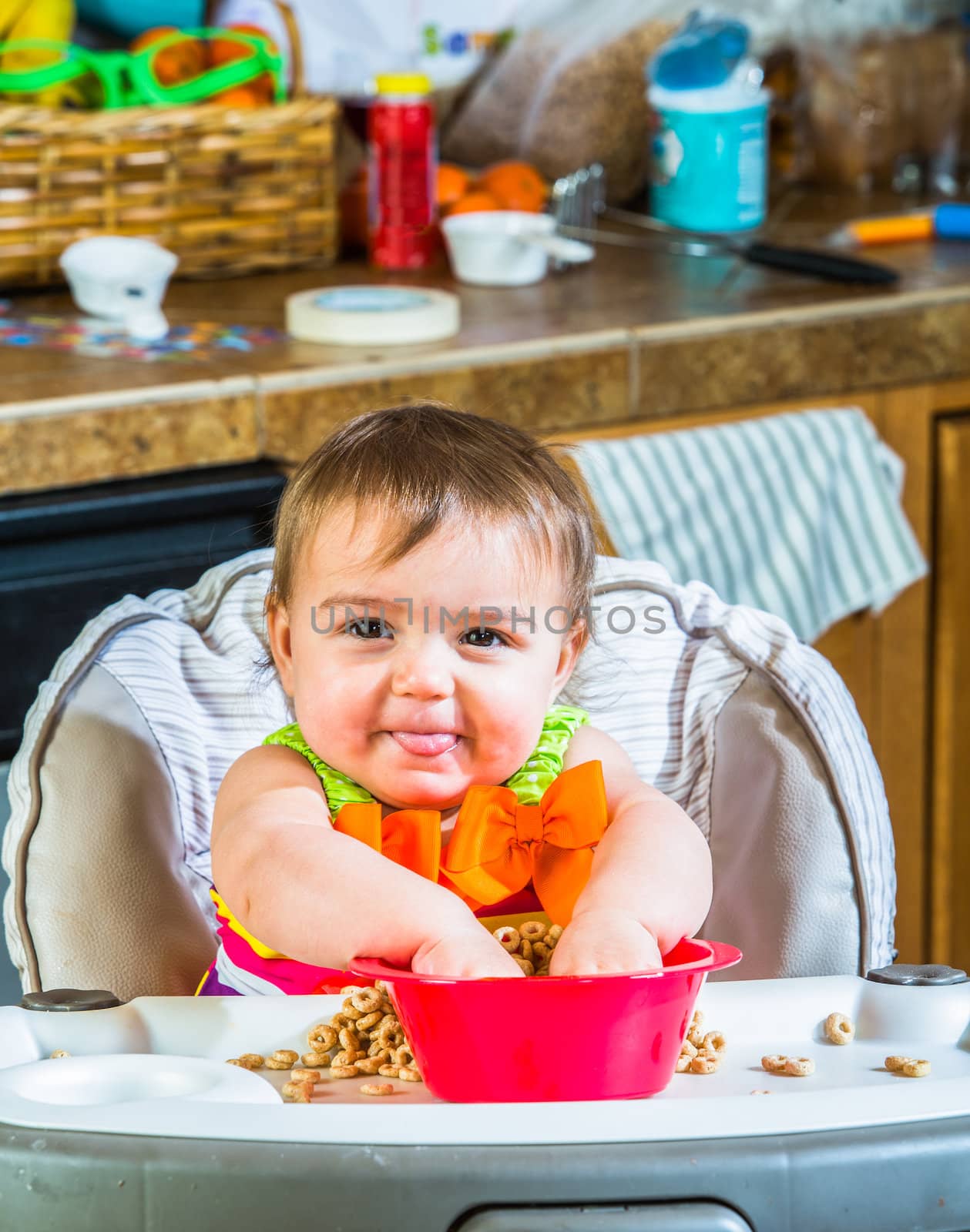 Baby girl eats breakfast in her highchair