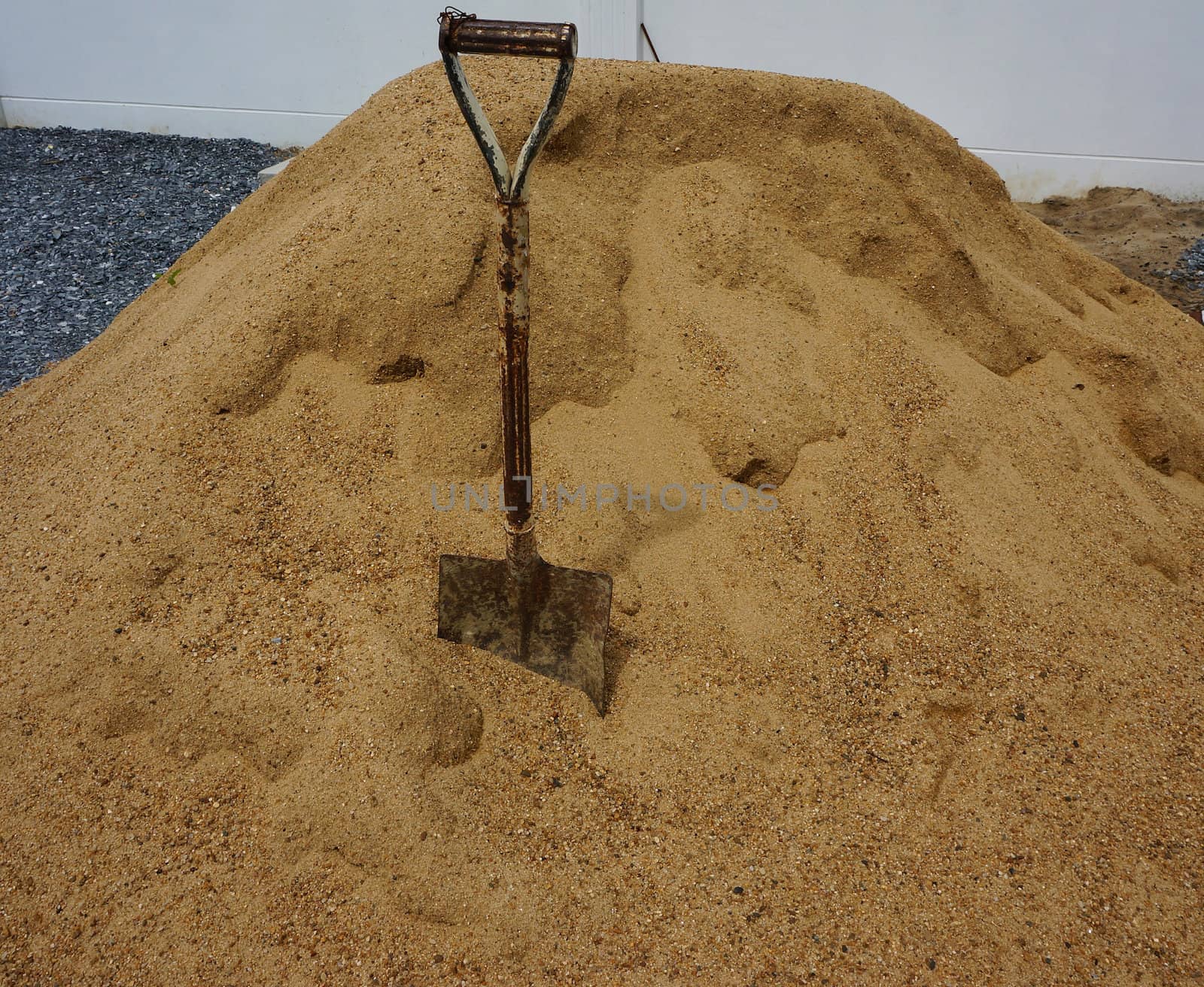 The old sand scoop made ??of steel with a rust brown, impaled on the sand.                              