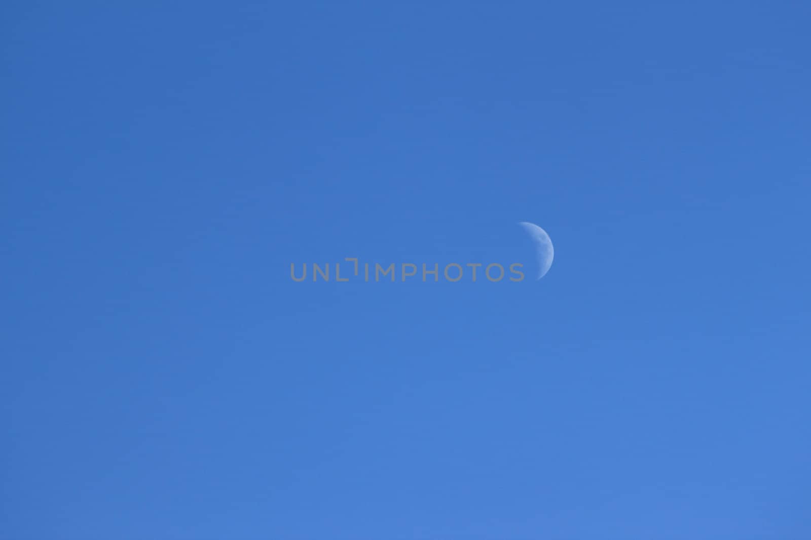 The moon in front of a beautiful blue sky