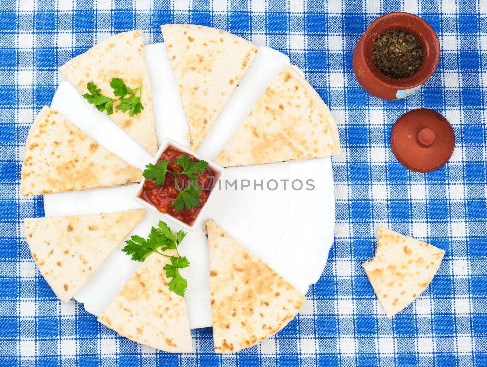 Sliced tortillas with basil on platter and blue napkin