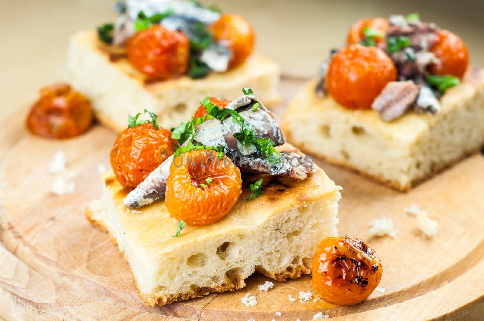 Delicious focaccia with sardines and cherry tomatoes on wood