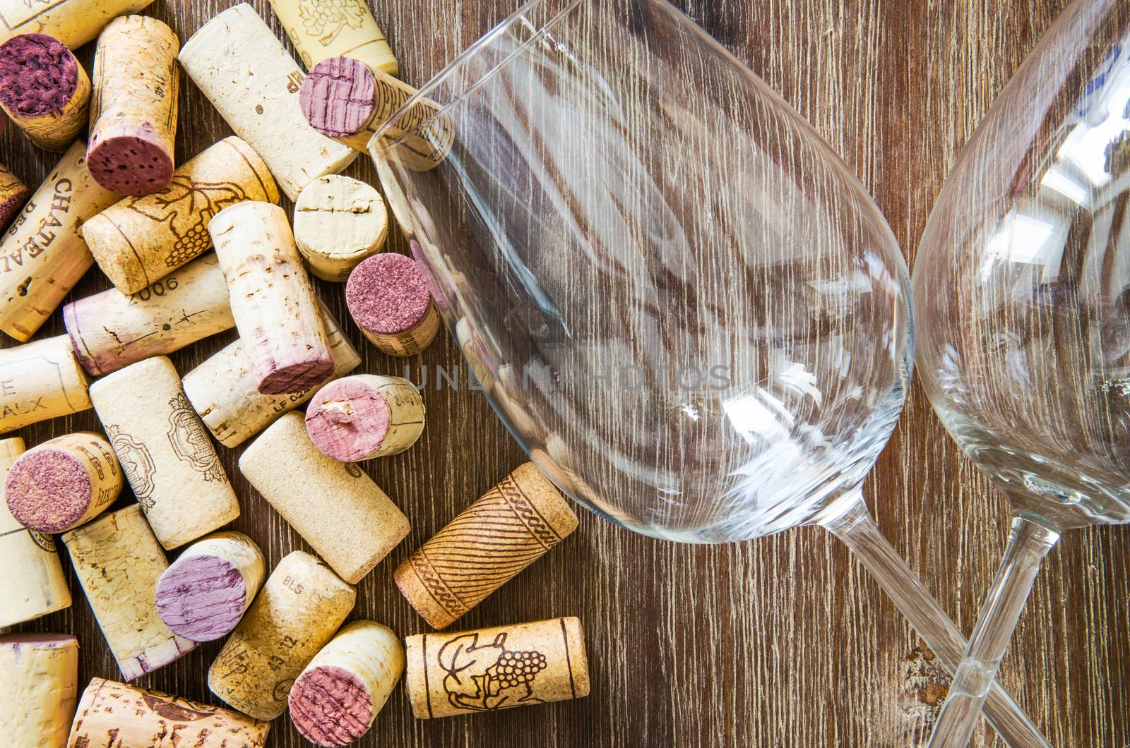 Detail of wine glasses and corks on textured wooden table