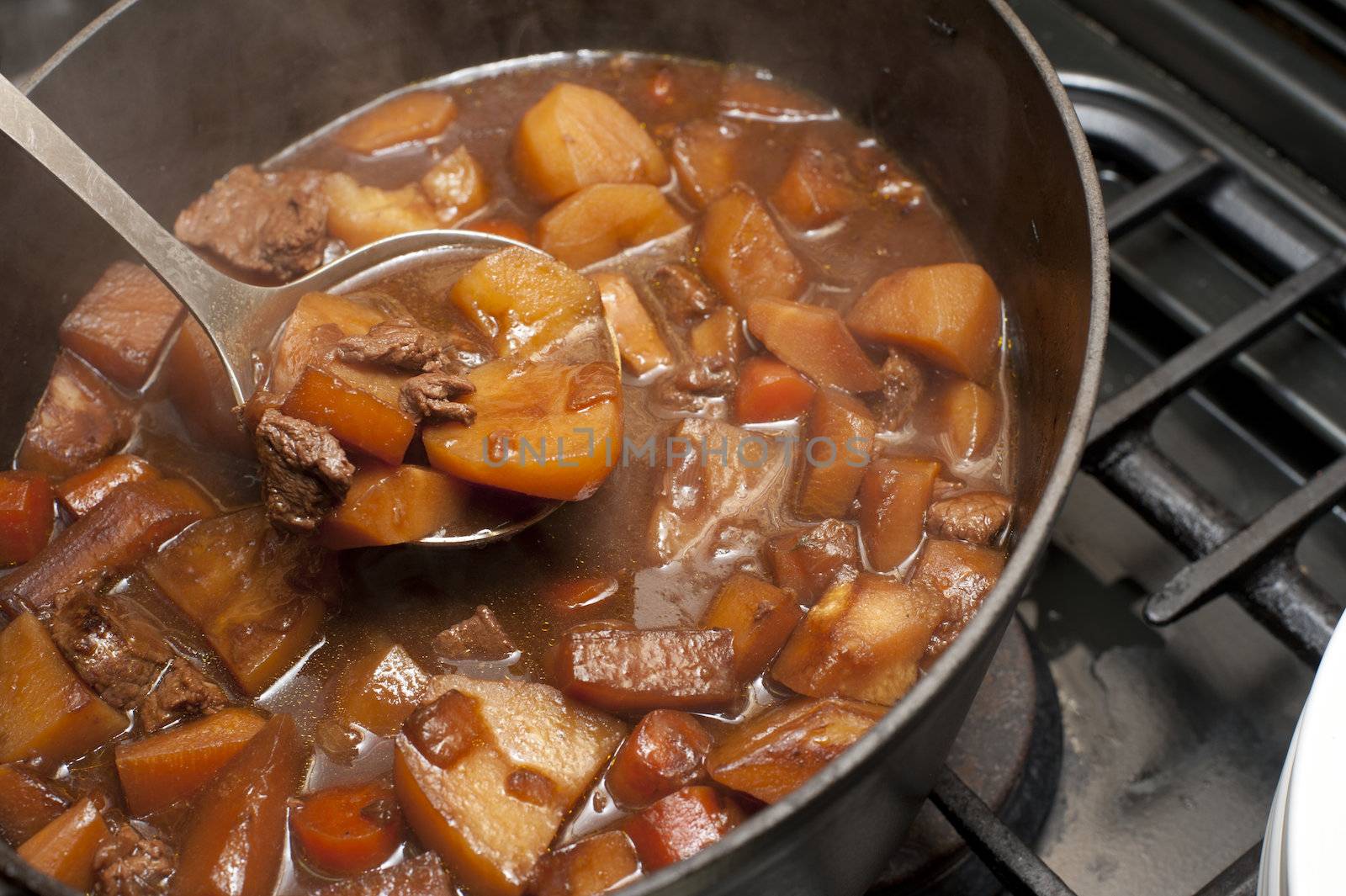 Delicious beef stew cooking in a pot in a rich gravy with potatoes and carrots for a traditional Lancashire Hotpot