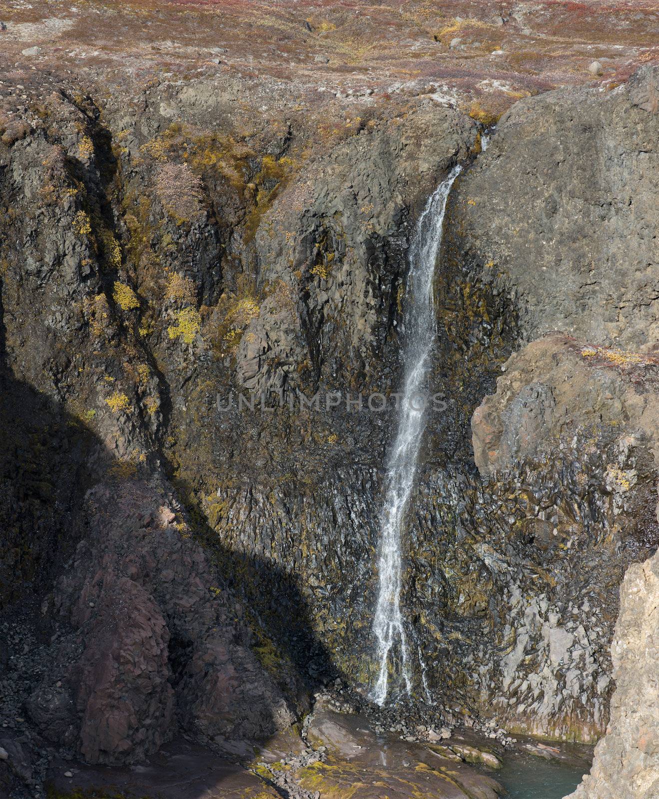 Closeup of a high waterfall in a rocky environment on Disko Island in Greenland