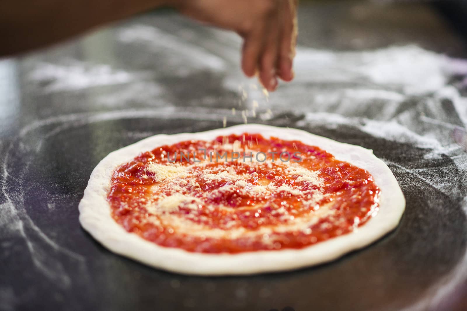 sprinkling cheese on home made italian pizza