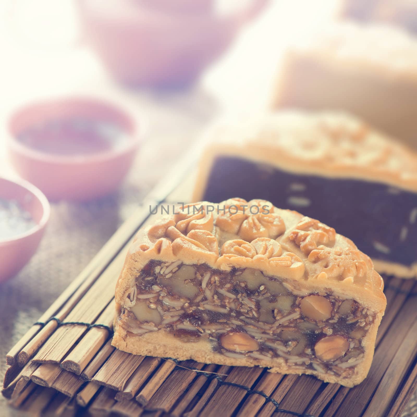 Traditional mooncakes on table setting with teacup. Retro vintage style Chinese mid autumn festival foods. The Chinese words on the mooncakes means assorted fruits nuts, not a logo or trademark.