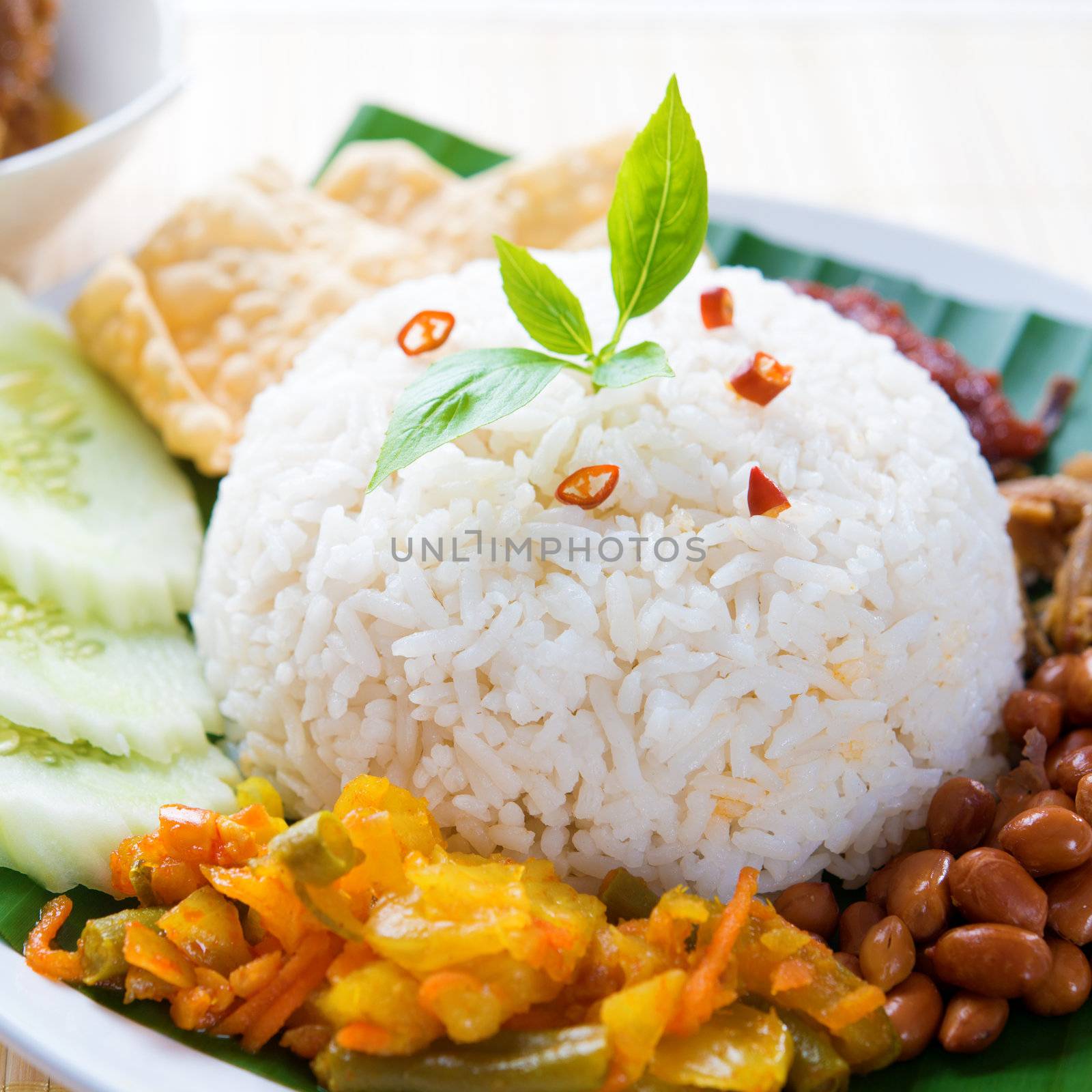 Nasi lemak kukus traditional malaysian spicy rice dish. Served with belacan, ikan bilis, acar, peanuts and cucumber. 