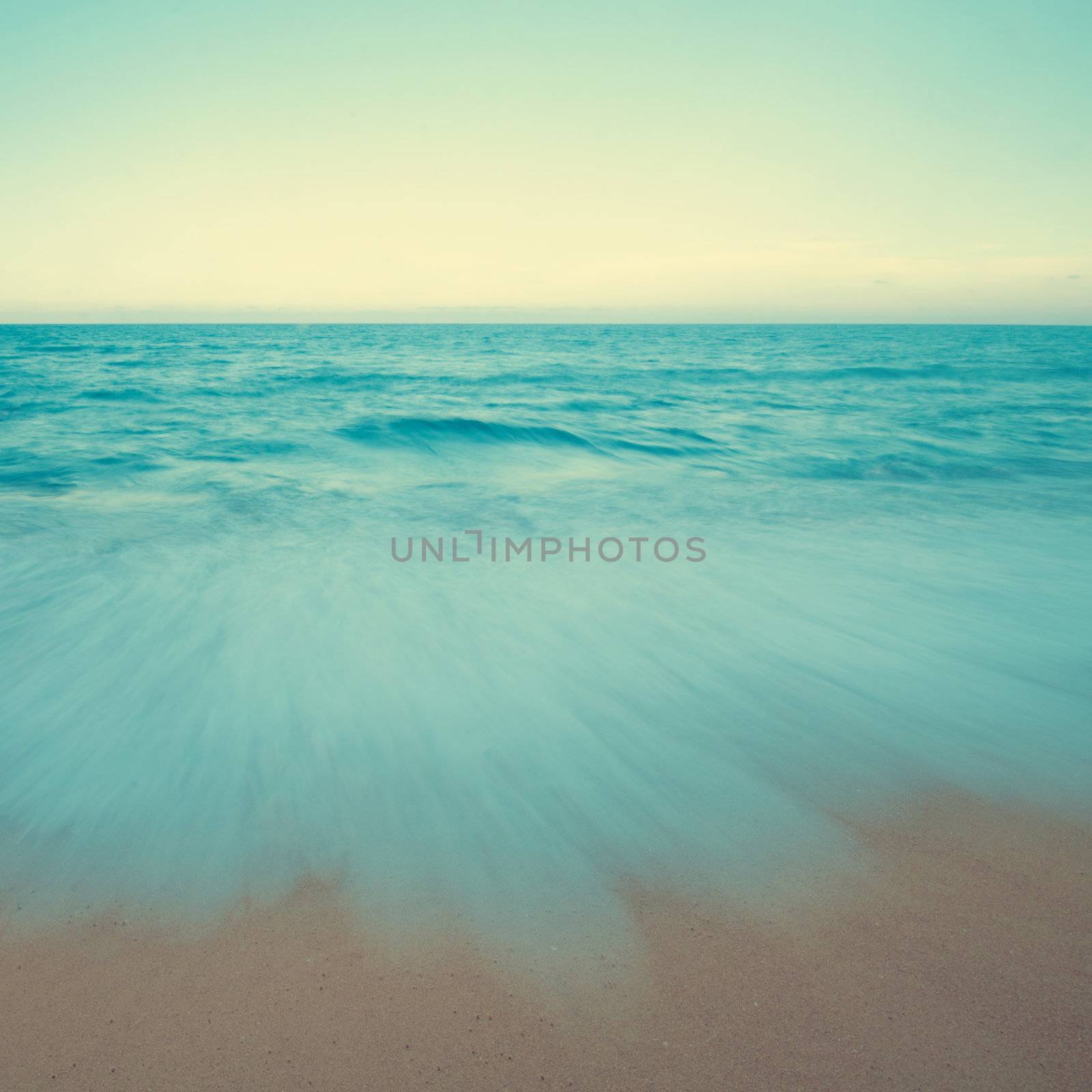 Vintage beach scene in sunset, slow shutter with moving waves.