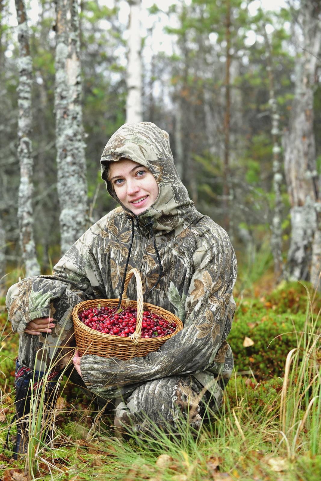 Young woman pick cranberry on a bog. Young woman pick cranberry on a bog.