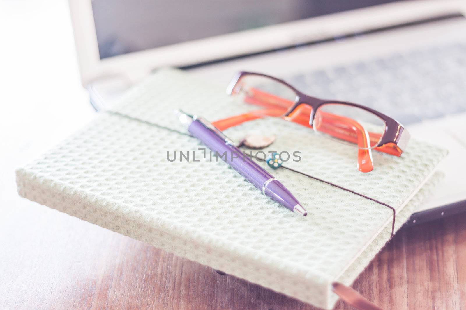 Notebook and eyeglasses with computer on wooden table, stock photo