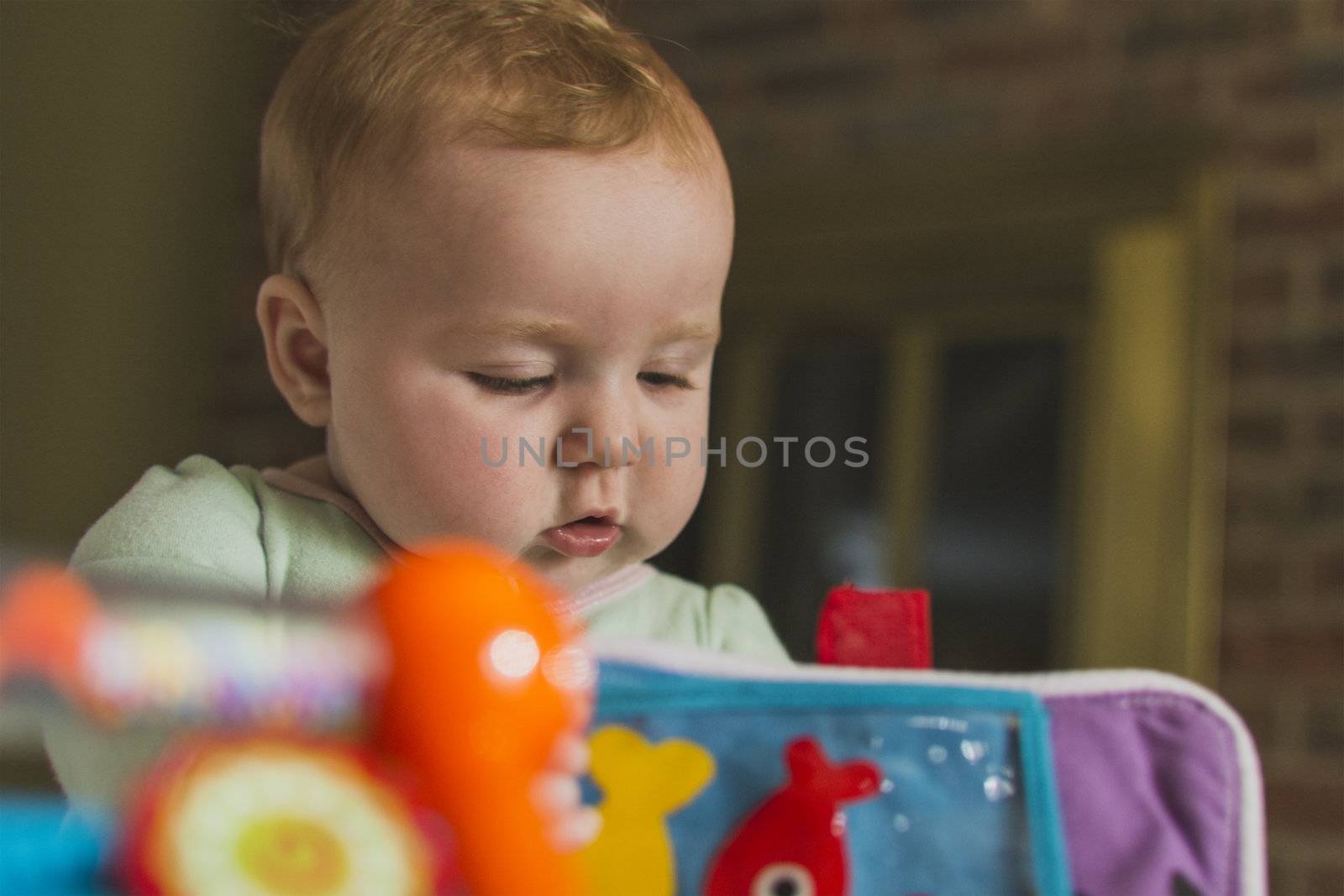 Peeking at baby looking down playing with colorful toys