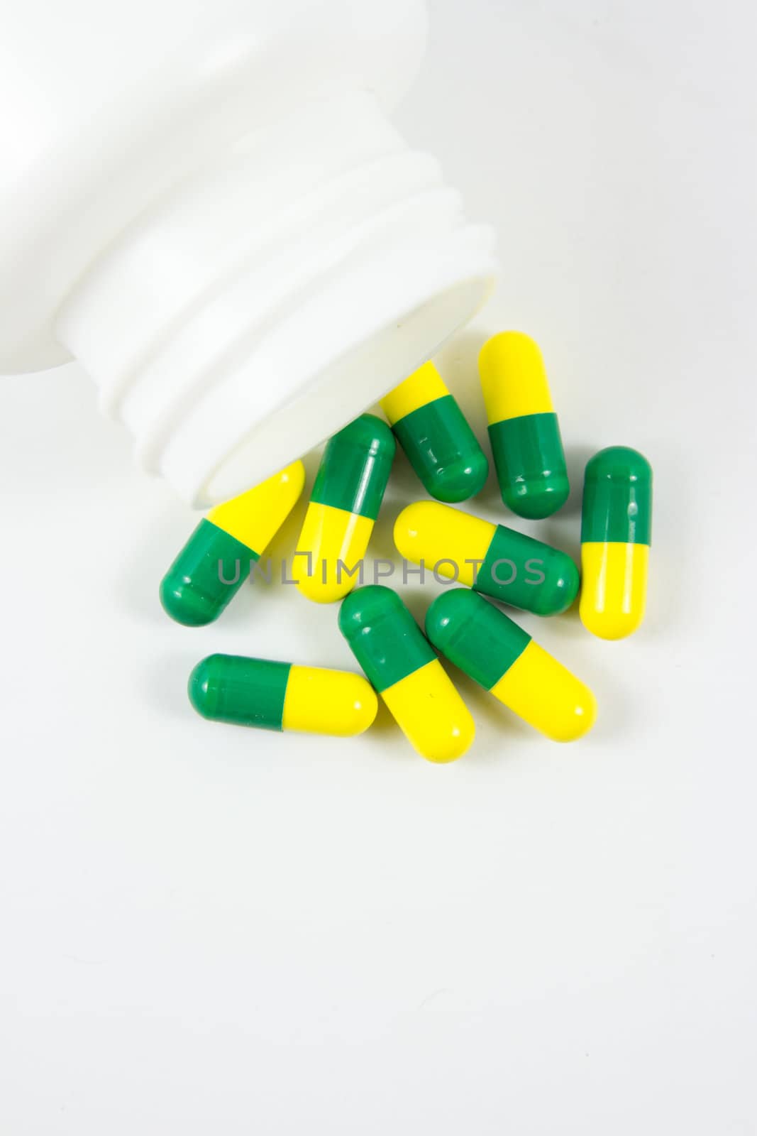 Green and yellow pills out of bottle by kasinv