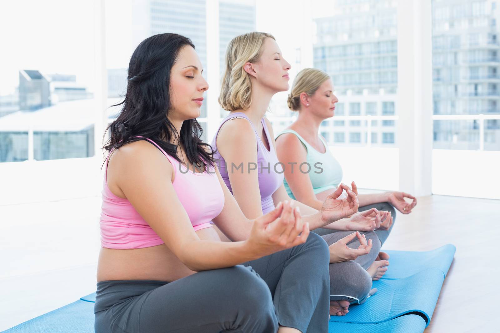 Relaxed pregnant women meditating in yoga class in a fitness studio