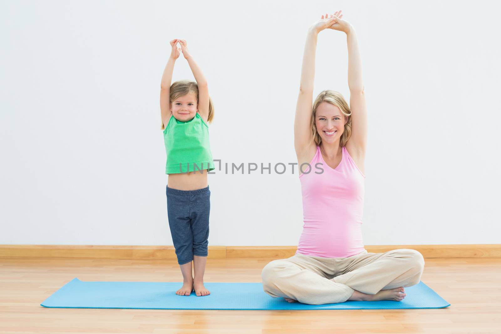 Pregnant mother and daughter doing yoga together by Wavebreakmedia