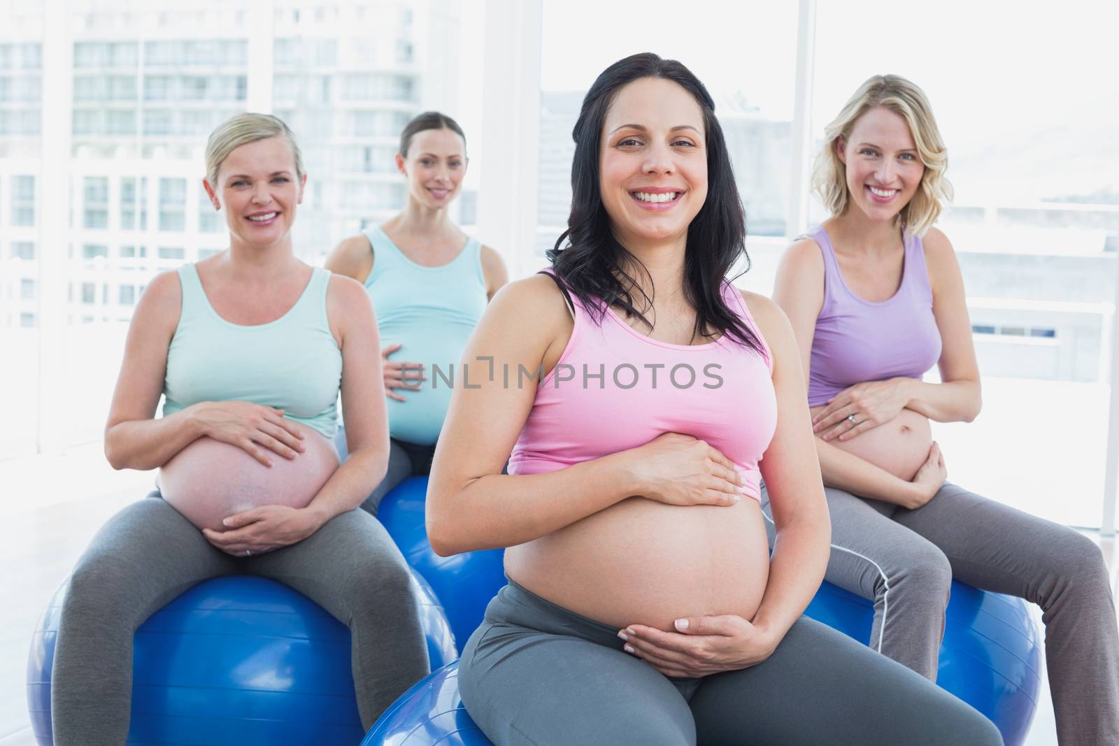 Smiling pregnant women sitting on exercise balls  in a fitness studio