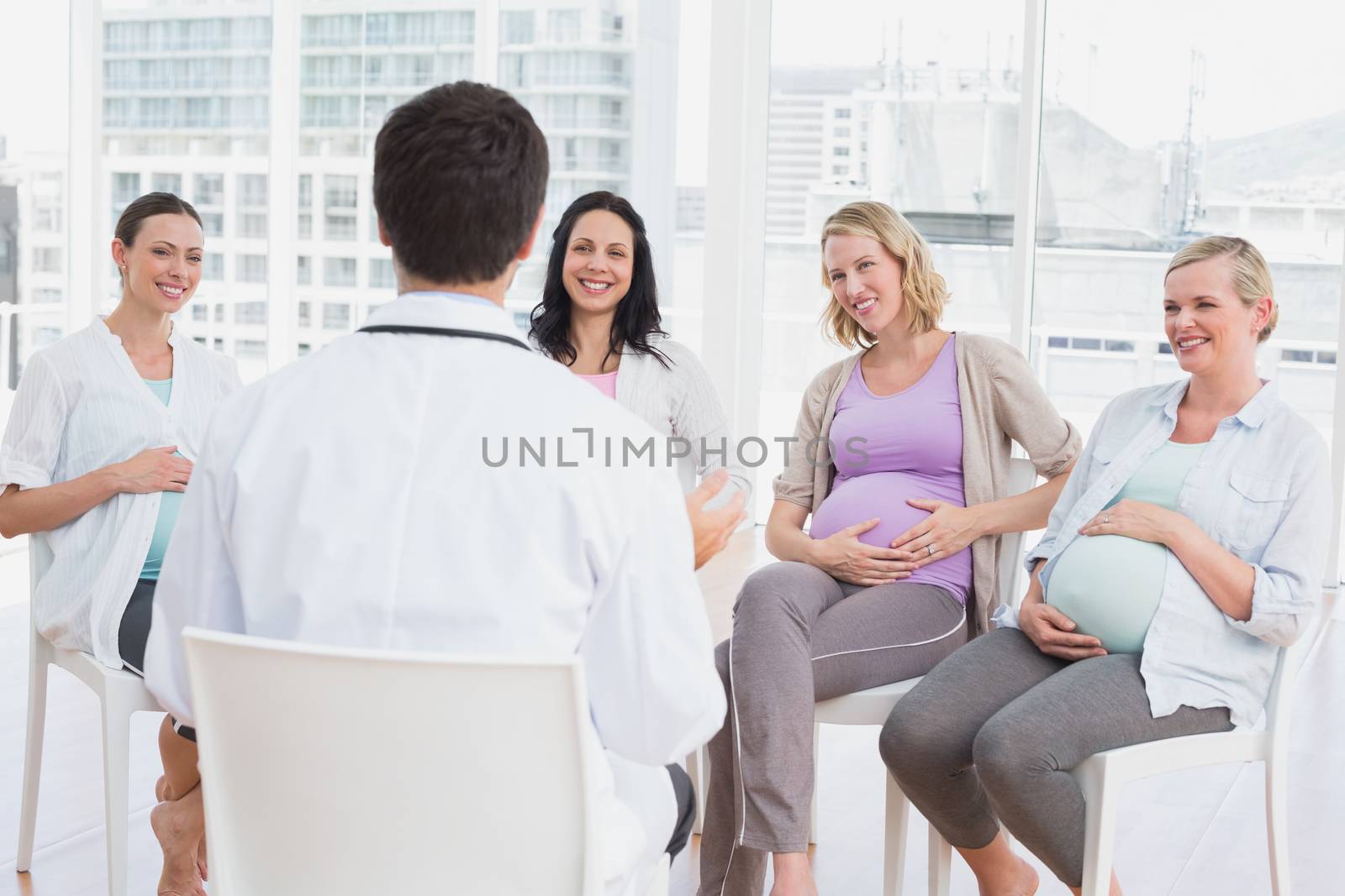 Smiling pregnant women listening to doctor at antenatal class at the hospital