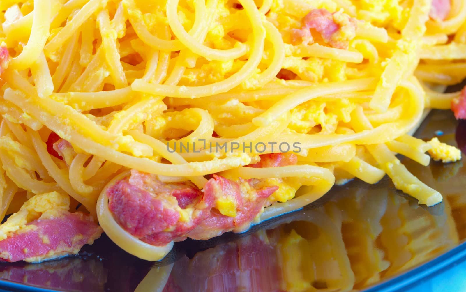 Pasta alla carbonara in close up, over black reflecting plate
