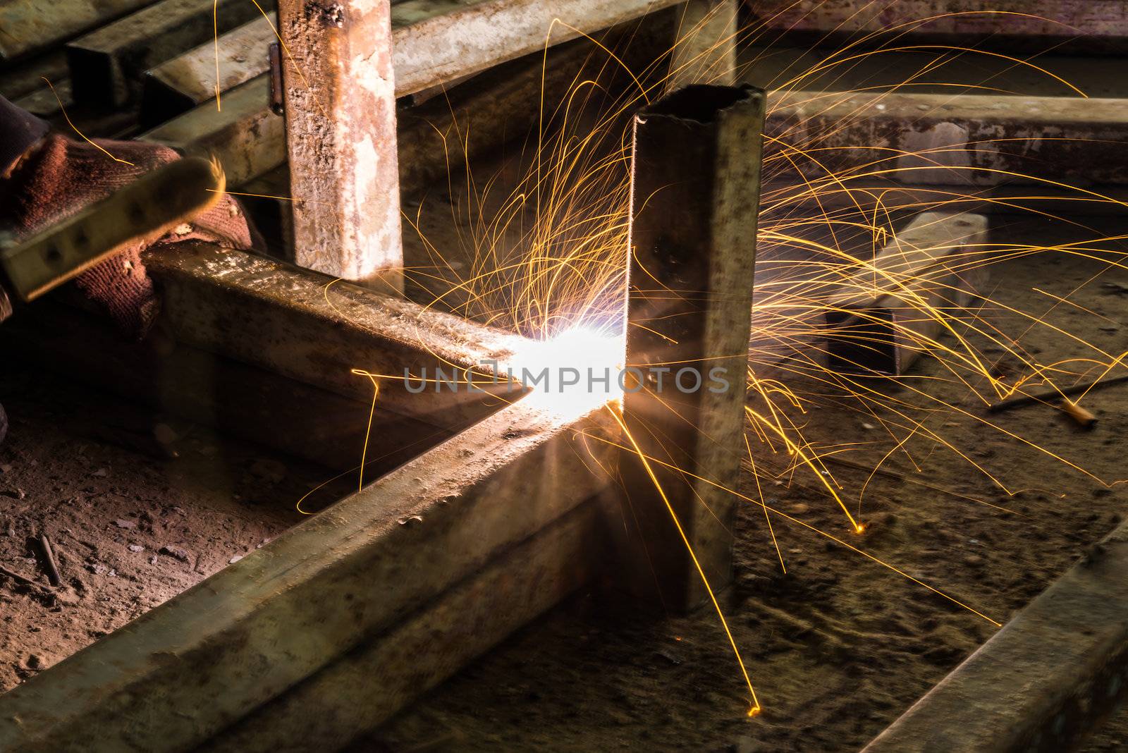 Worker are welding steel on low light.