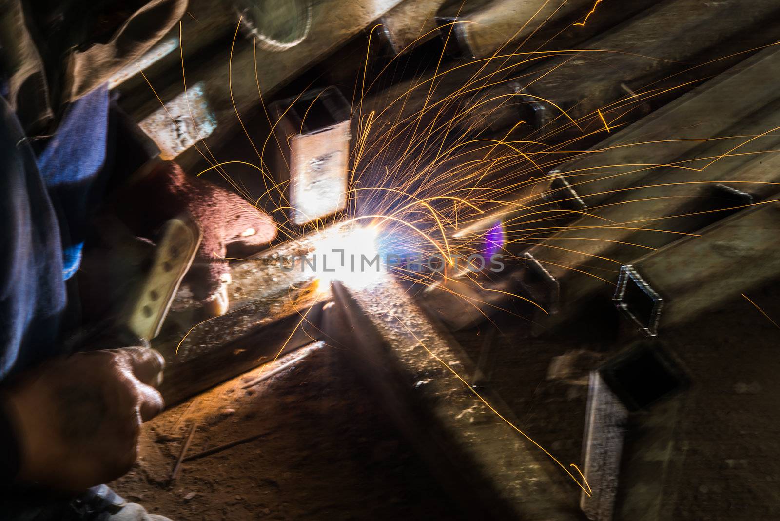 Worker are welding steel on low light.