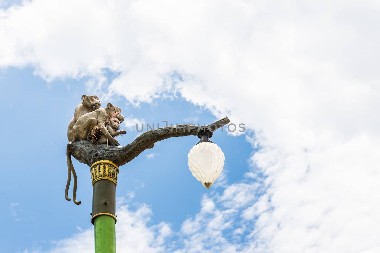 Statue of a monkey family on lamp post on blue sky. by wmitrmatr
