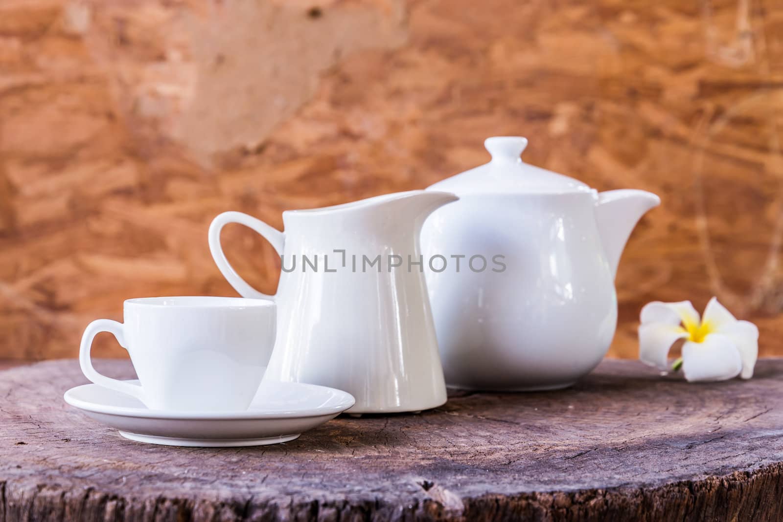 White cup with white tea pot on wood background