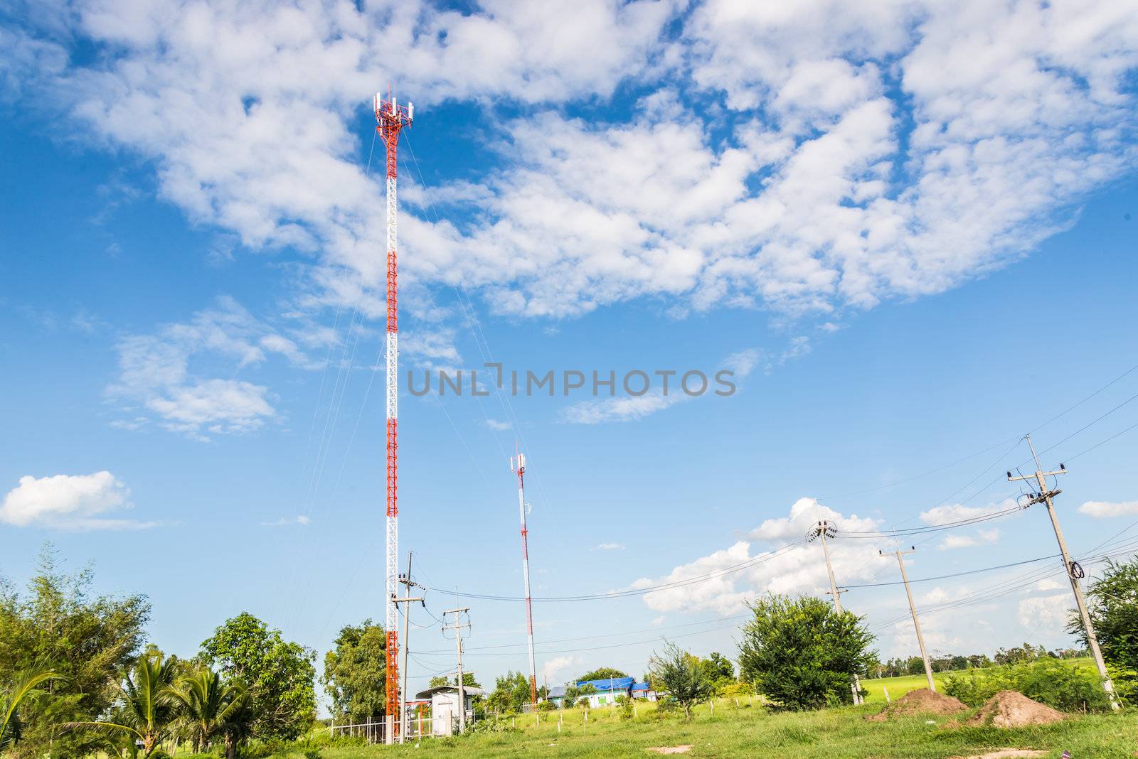 Red and white tower of communications with a lot of different antennas under clear sky.