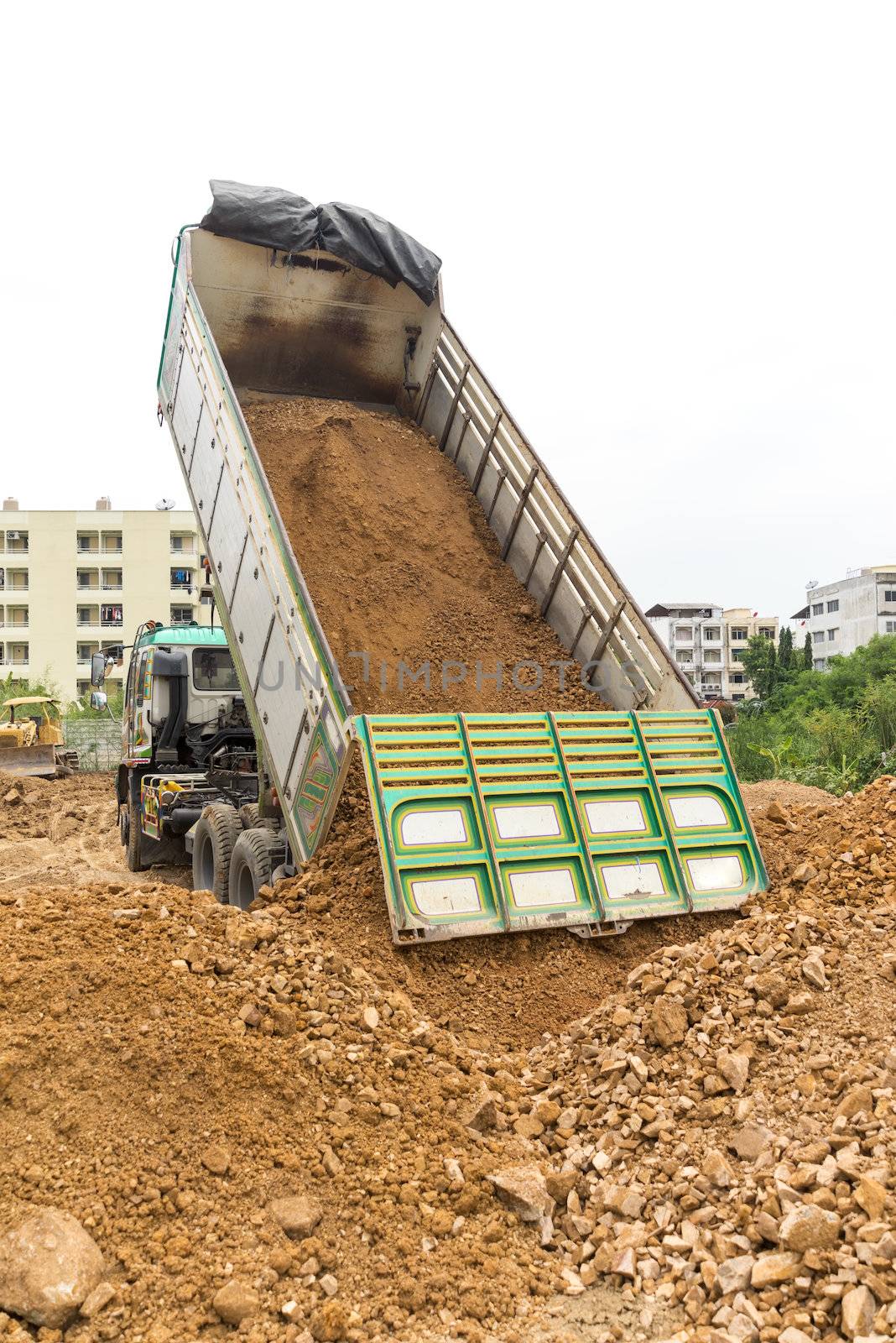 Dump truck dumps its load of rock and soil on land by iamway