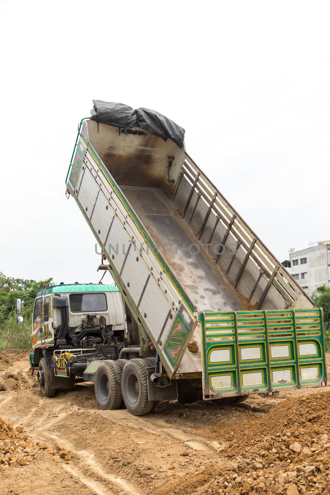 Dump truck dumps its load of rock and soil on land by iamway