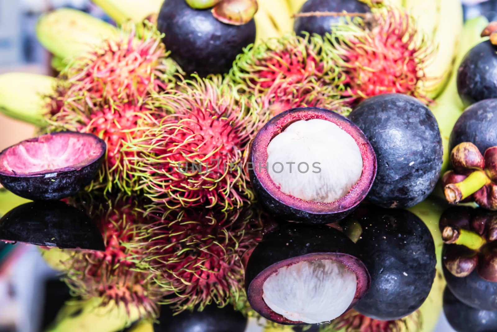 Selection Of Tropical Fruits on black glass background.