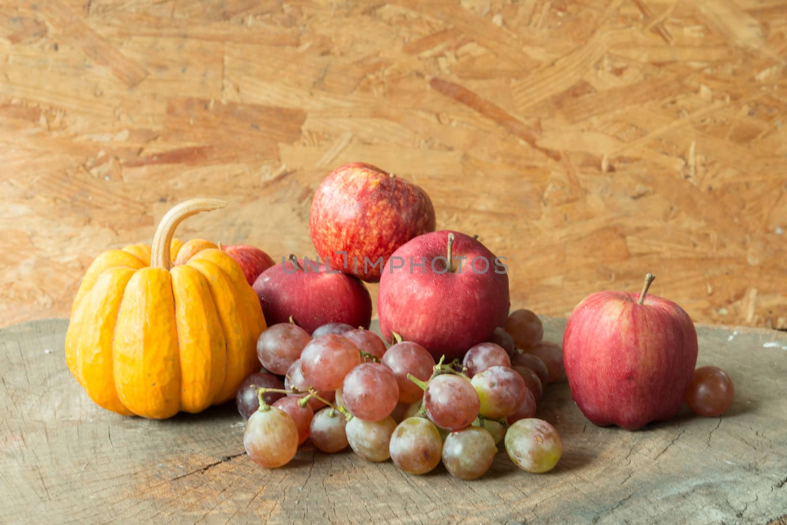 Still life red apples and grapes and pumpkin on old wood.
