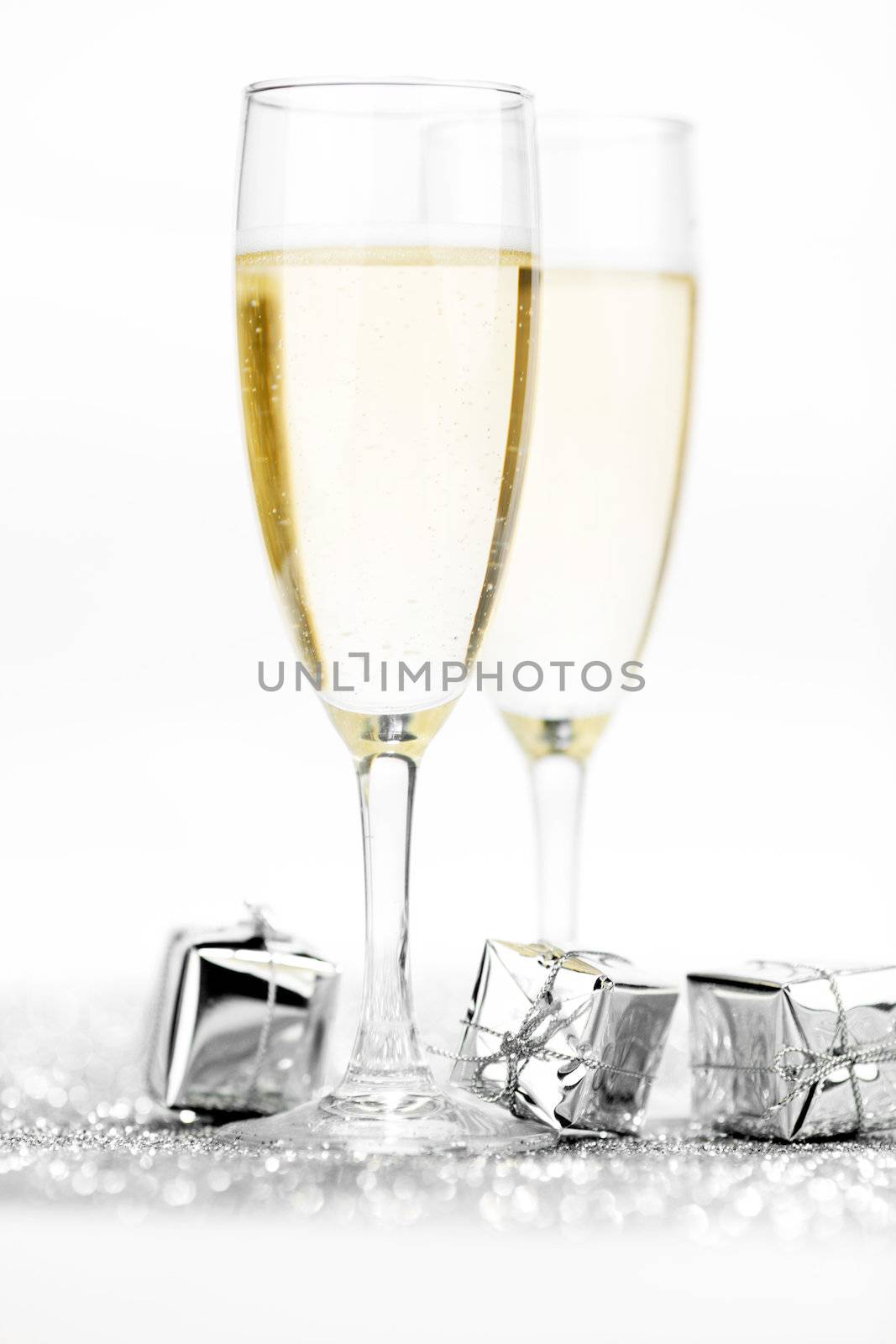 Glasses of champagne and christmas gifts on silver background