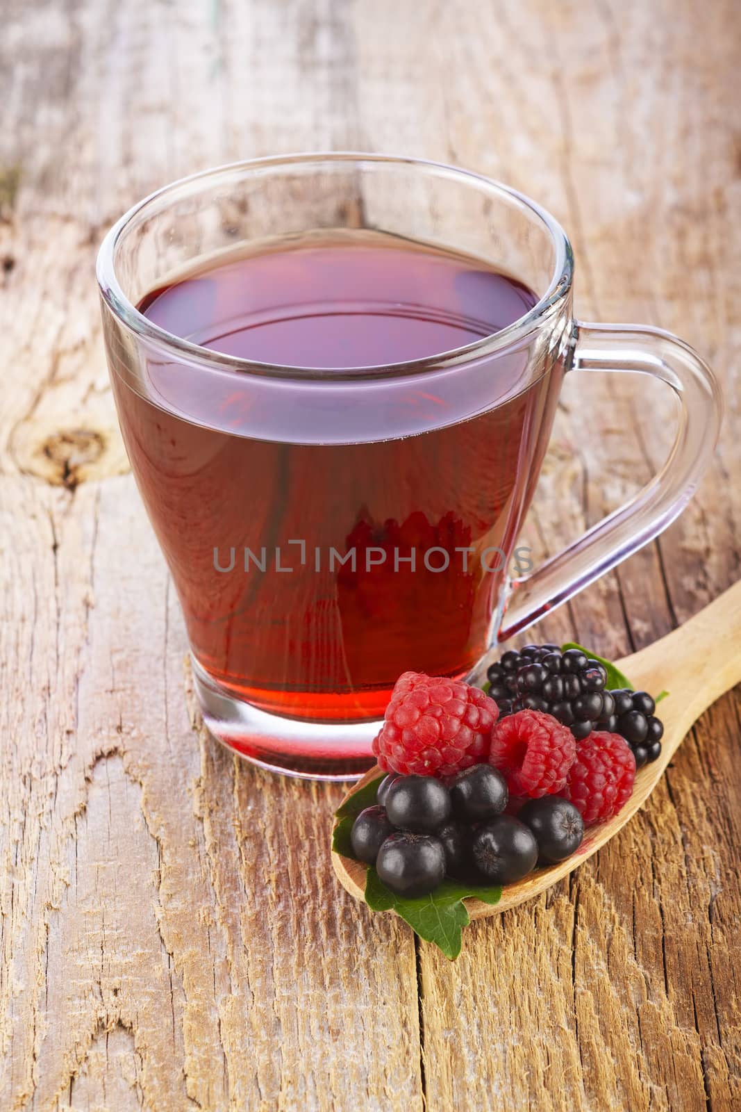 Fruit red tea with wild berries in wooden spoon on brown wooden table