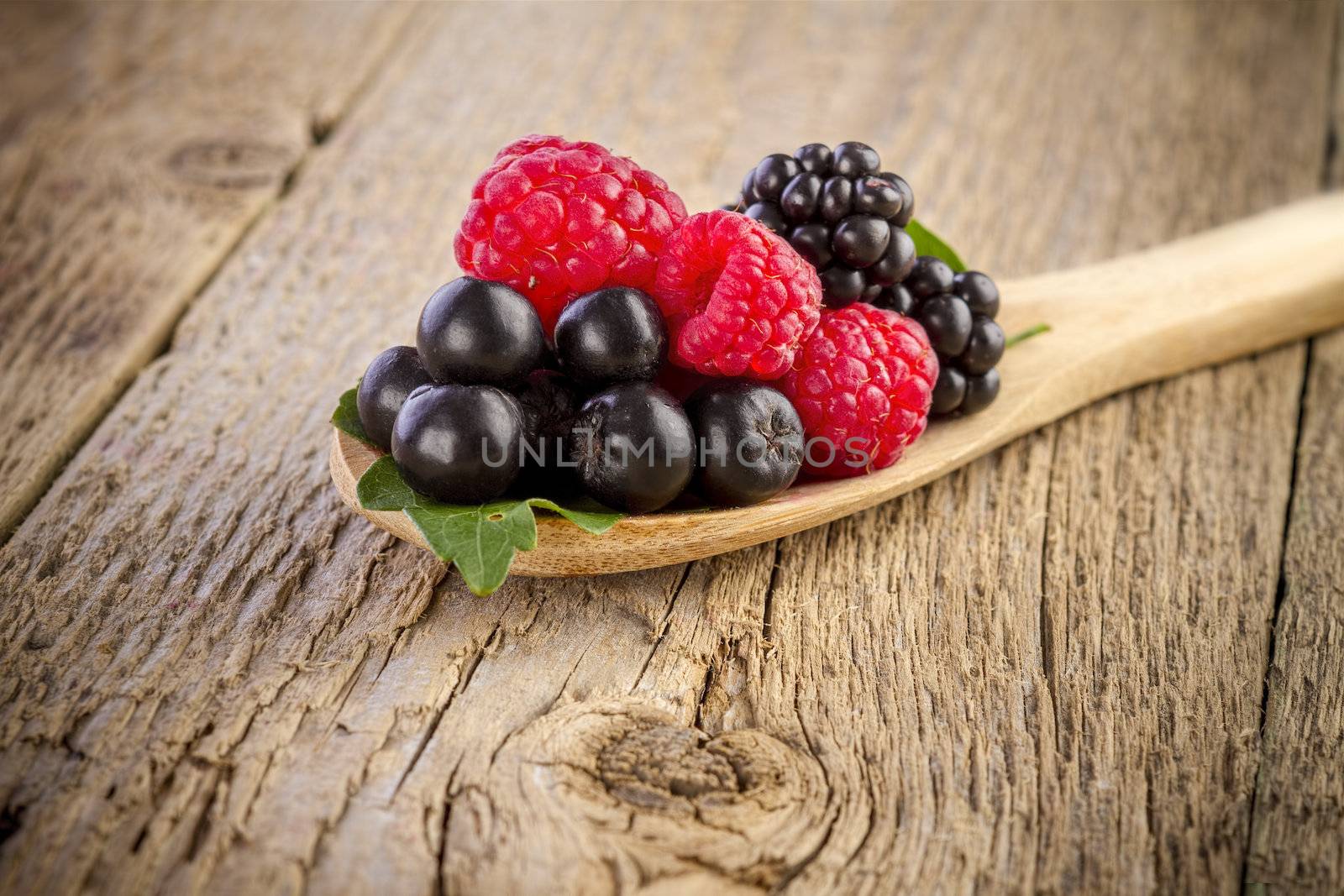 Fresh berries in wooden spoon on wooden table