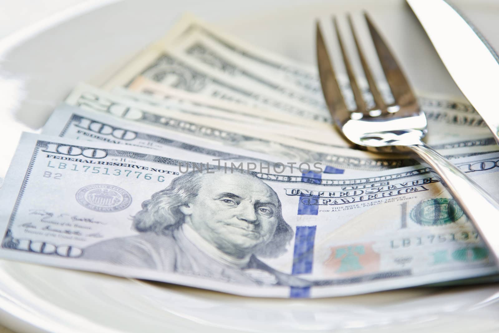 American Dollar note on white plate by cutlery