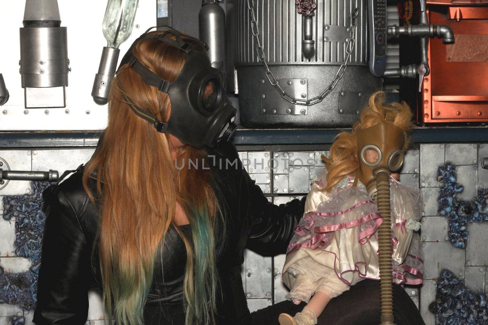 Woman with a gasmask and a puppet in front of a a wall.