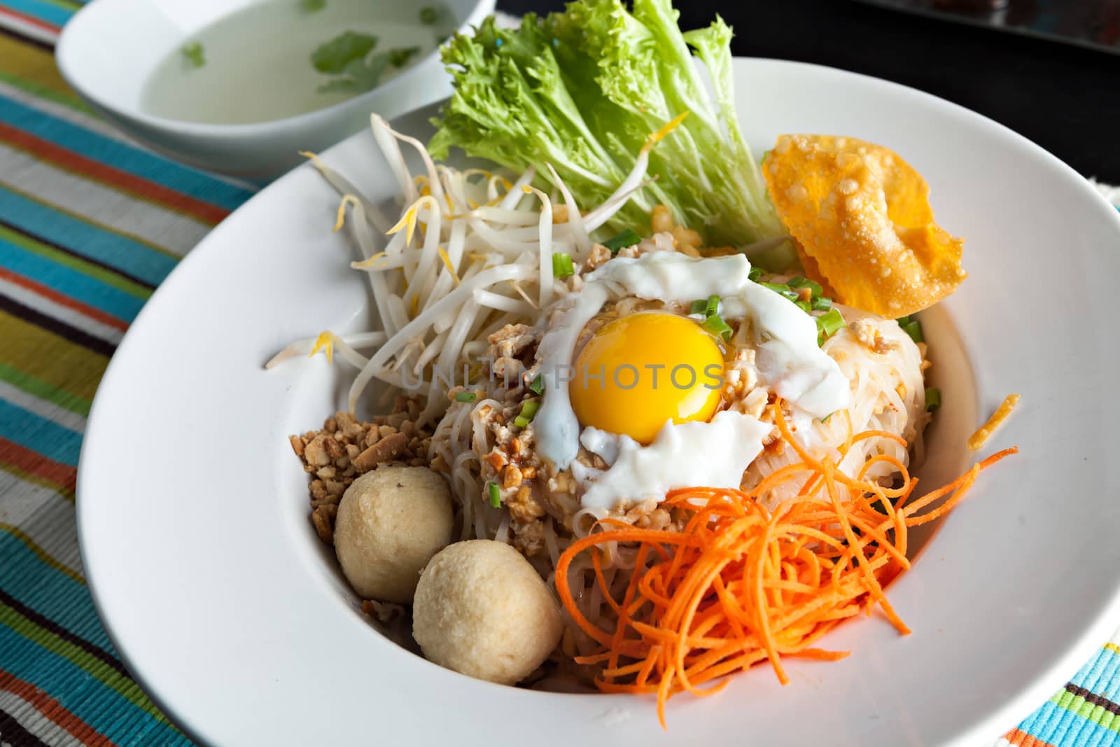 Gai pad bai gaprow style Thai dish with fried egg and rice noodles.