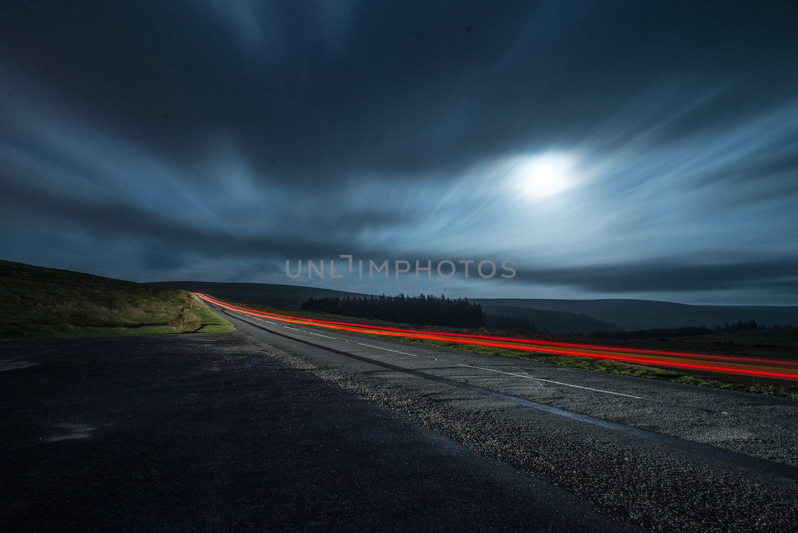 Blur light in night shoot of fast driving car with blurred clouds over full super moon and road