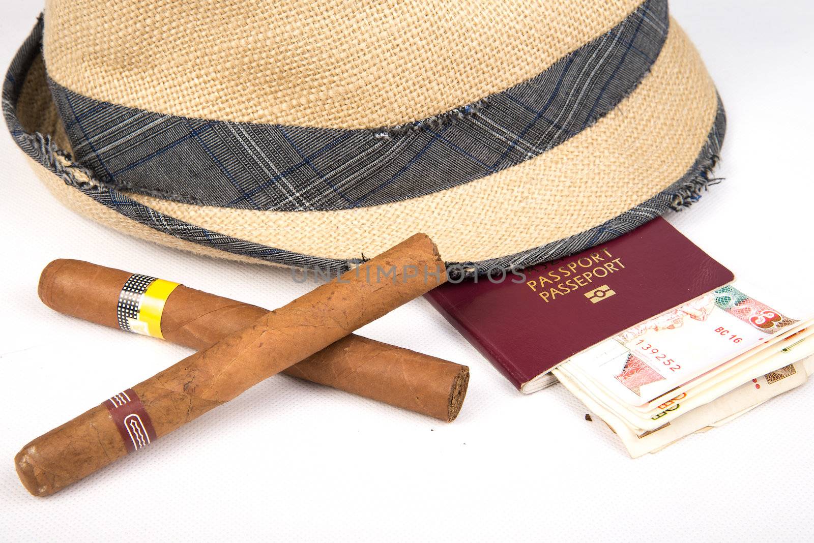 Cuban cigars and hat with passport and cuban currency pesos  on white isolated background